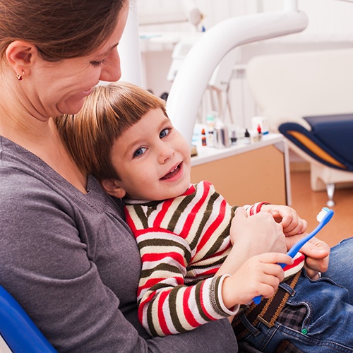 Little boy sitting in mother’s lap at dentist