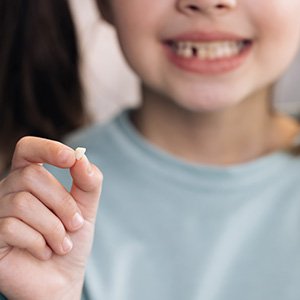 Smiling girl holding her extracted tooth
