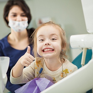 Child smiling while giving thumbs up in treatment room