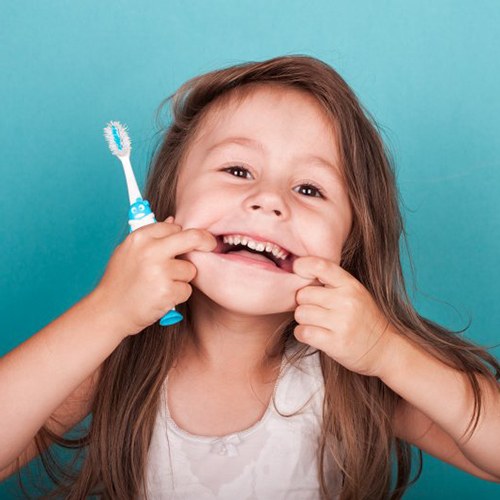 Cute little girl makes funny face with toothbrush