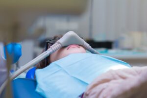 Child undergoing sedation at the dentist office laid back in dentist’s chair.